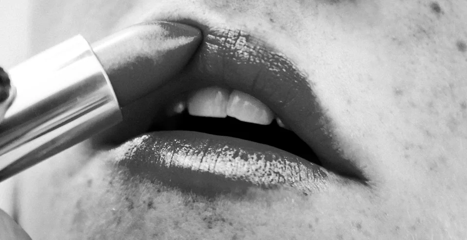 Black-and-white close-up of lipstick being applied to a person's lips
