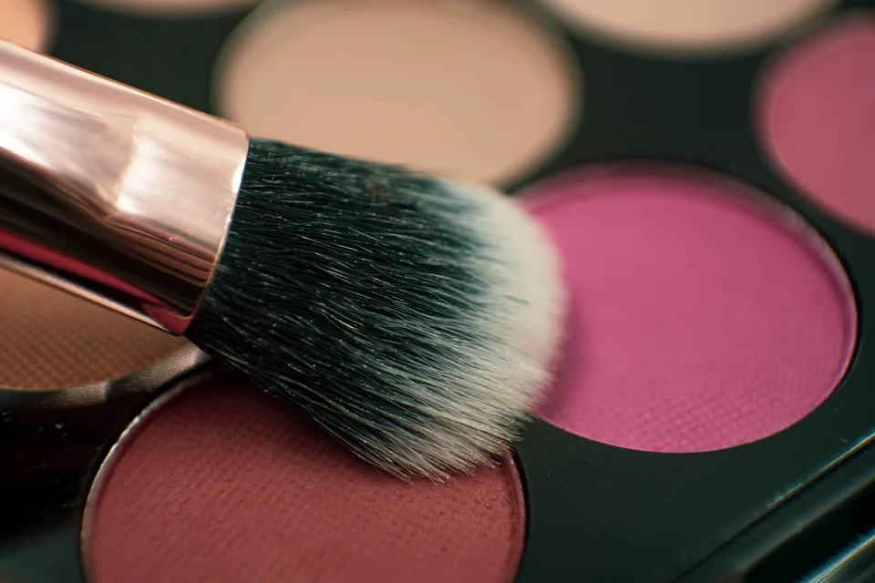 Close-up of a makeup brush resting over a powder palette