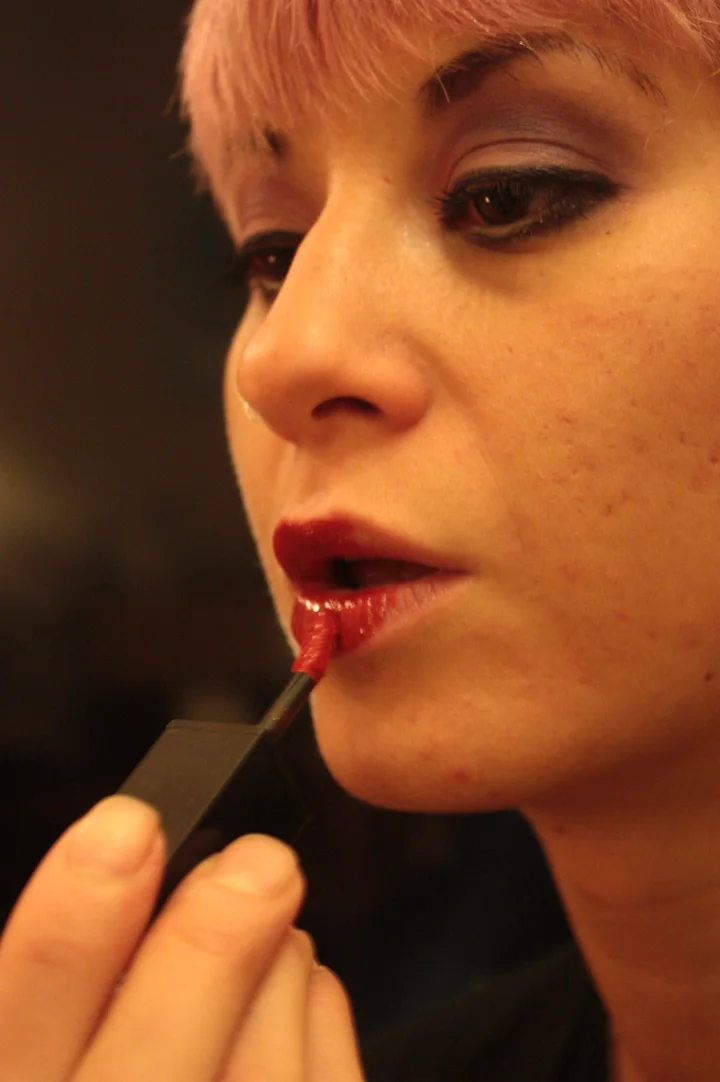 Model applying red liquid lipstick with a wand