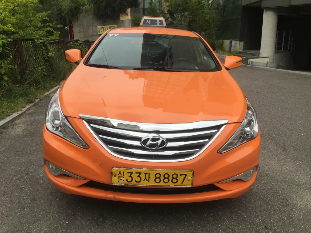 Orange Seoul sedan taxi parked in daylight
